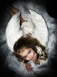 High angle portrait of cute girl in fairy costume sitting at home