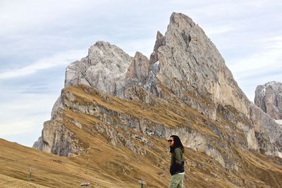 Woman standing on rocky mountain against sky