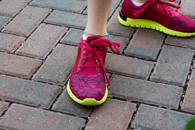 Low section of woman wearing sports shoes on footpath