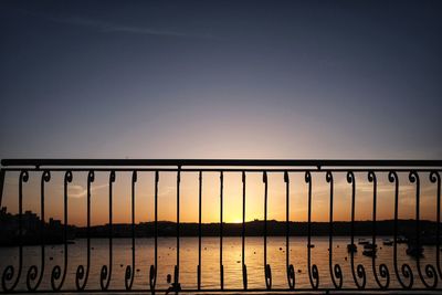 Silhouette railing against clear sky during sunset