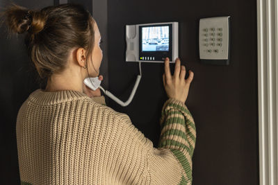 Woman using intercom device at home