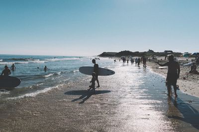 People on beach against clear sky
