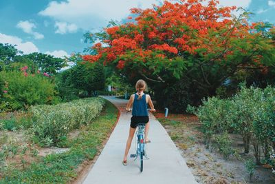 Girl riding bicycle against trees