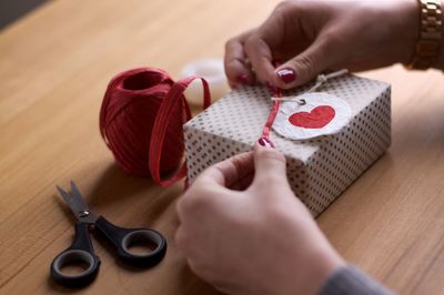 Midsection of woman holding heart shape on table