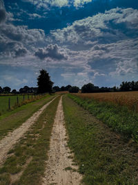 Road amidst field against sky - mecklenburg-vorpommern - gravel 
