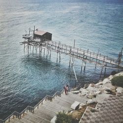 High angle view of people on steps by pier on sea