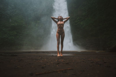 Young woman standing against waterfall