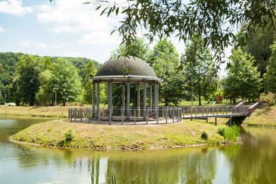 Gazebo by lake in park against sky