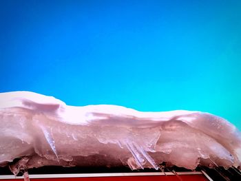 Low angle view of icicles against clear blue sky