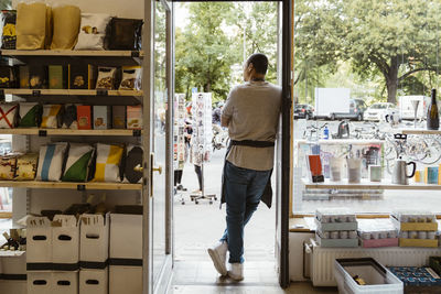 Rear view of male owner standing at store doorway