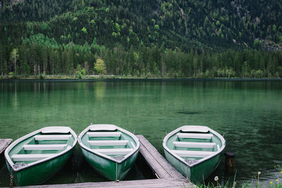 Boats moored in lake against trees