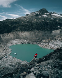 People on rock by mountain against sky