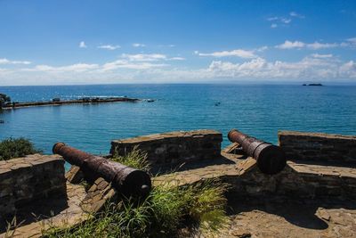 Old rusty bollard by sea against sky