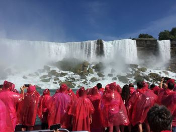 People in pink raincoat against waterfall