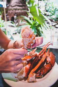 Cropped image of woman eating crab in restaurant