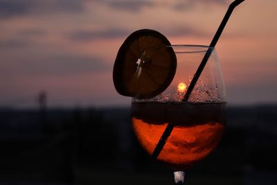 Close-up of drink against sky during sunset