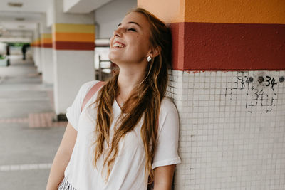 Smiling woman standing against column