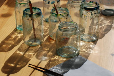 High angle view of empty glass jars with paintbrushes on table