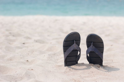 Close-up of shoes on beach