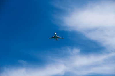 Low angle view of commercial airplane flying against blue sky