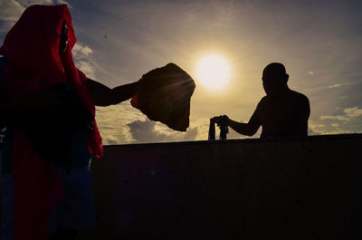 Silhouette people against sun during sunset