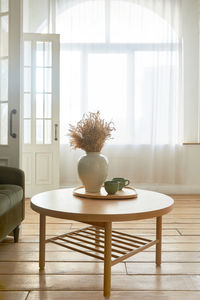 Vase with flowers on table in room