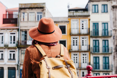 Rear view of woman standing by buildings in city