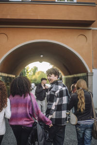 Smiling teenage boy looking over shoulder while walking with friends