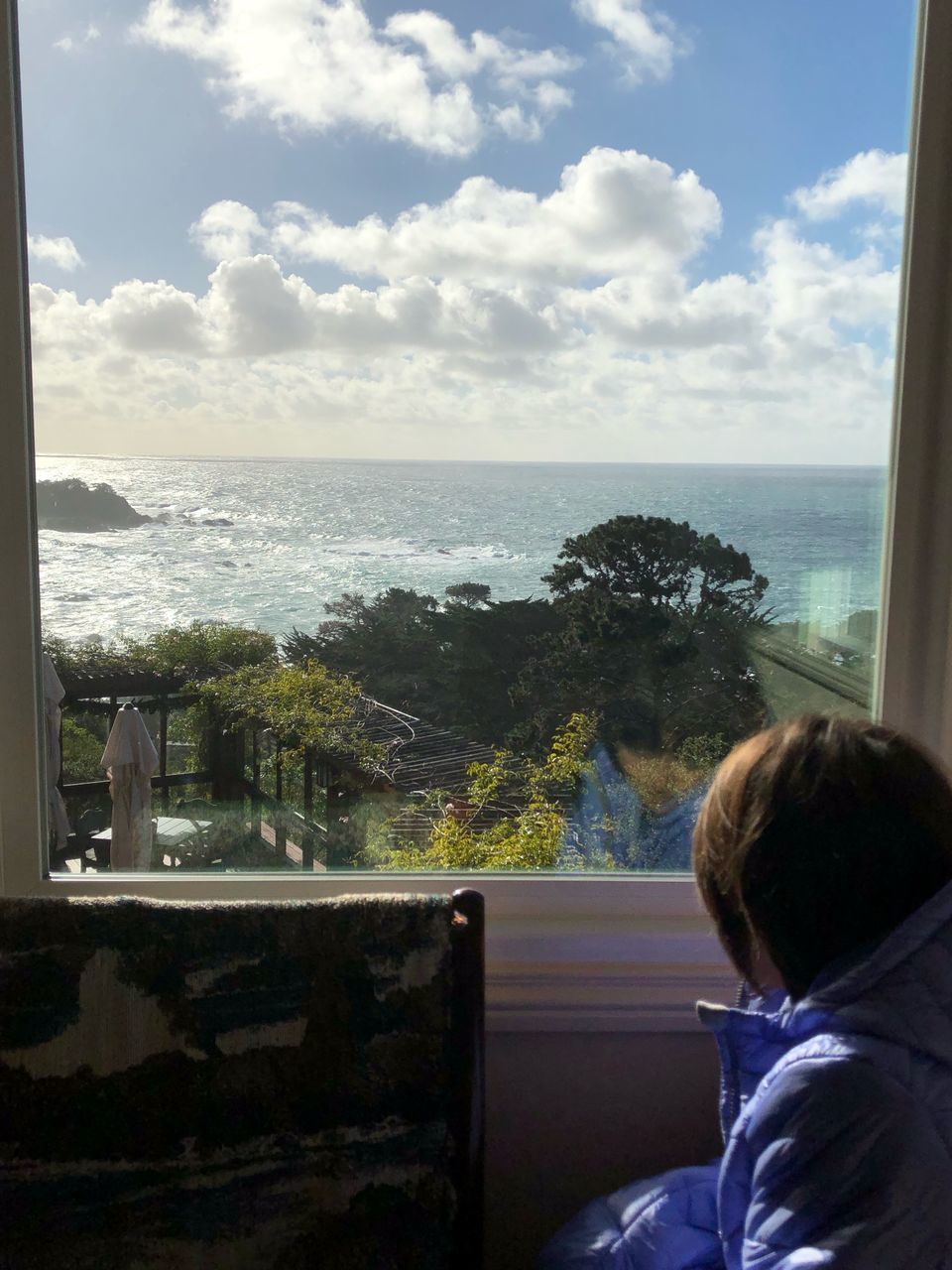 REAR VIEW OF A BOY LOOKING AT SEA