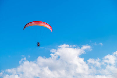 Low angle view of person paragliding against sky