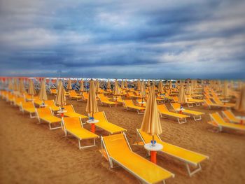 Empty chairs on beach against sky