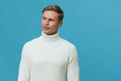 Portrait of young man standing against blue background