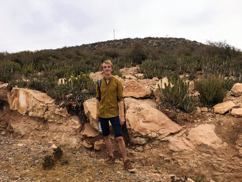 Full length portrait of young man standing against mountain on field