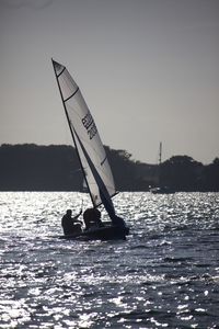 Silhouette man on boat in sea against clear sky