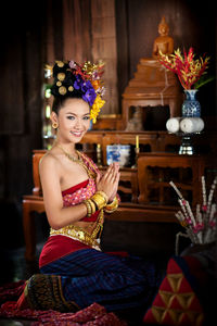 Portrait of smiling young woman in traditional clothing sitting on floor