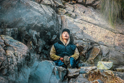 Young man sitting on rock