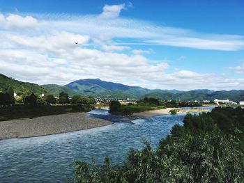 Scenic view of river by mountains against sky