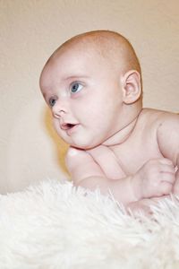 Close-up of cute baby boy against wall at home