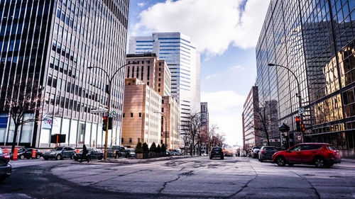 City street by modern buildings against sky