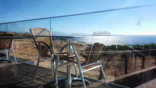 Chairs and table by sea against sky