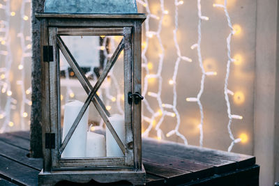 Close-up of illuminated lamp against window at sunset