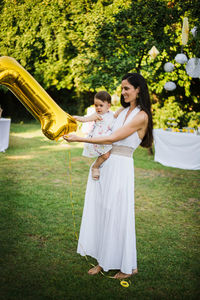Happy friends standing on grass against plants