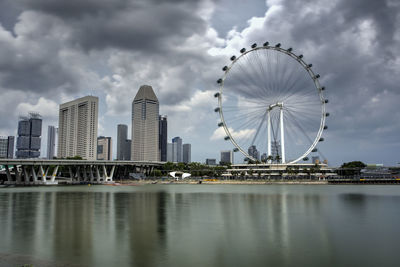 Ferris wheel in city against cloudy sky