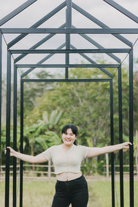 Portrait of a smiling young woman standing against plants