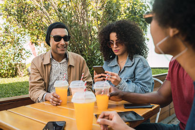 Young couple holding mobile phone while sitting on table