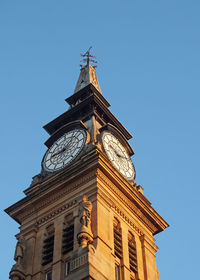 Low angle view of clock tower against blue sky