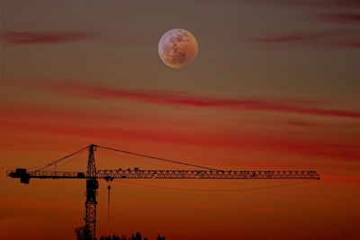 Silhouette of crane against sky during sunset