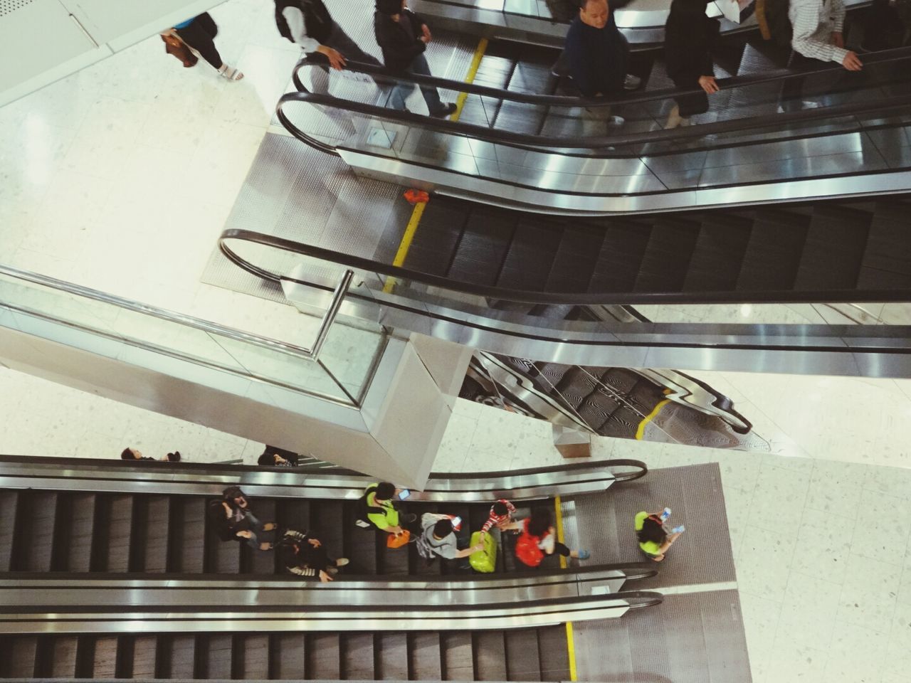 indoors, men, lifestyles, person, high angle view, large group of people, leisure activity, walking, medium group of people, standing, escalator, steps, city life, shopping, staircase, steps and staircases, tiled floor, shopping mall, railing