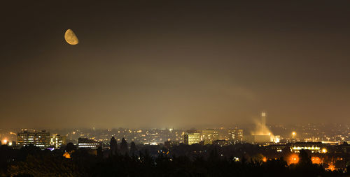 Illuminated cityscape against sky at night