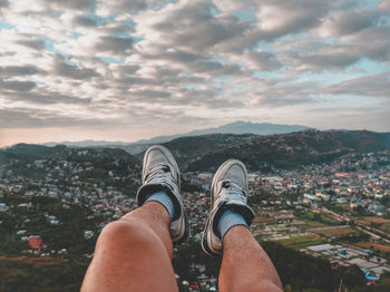 Low section of man with cityscape against sky